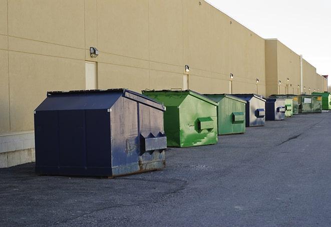 a construction worker disposing of debris into a dumpster in Augusta